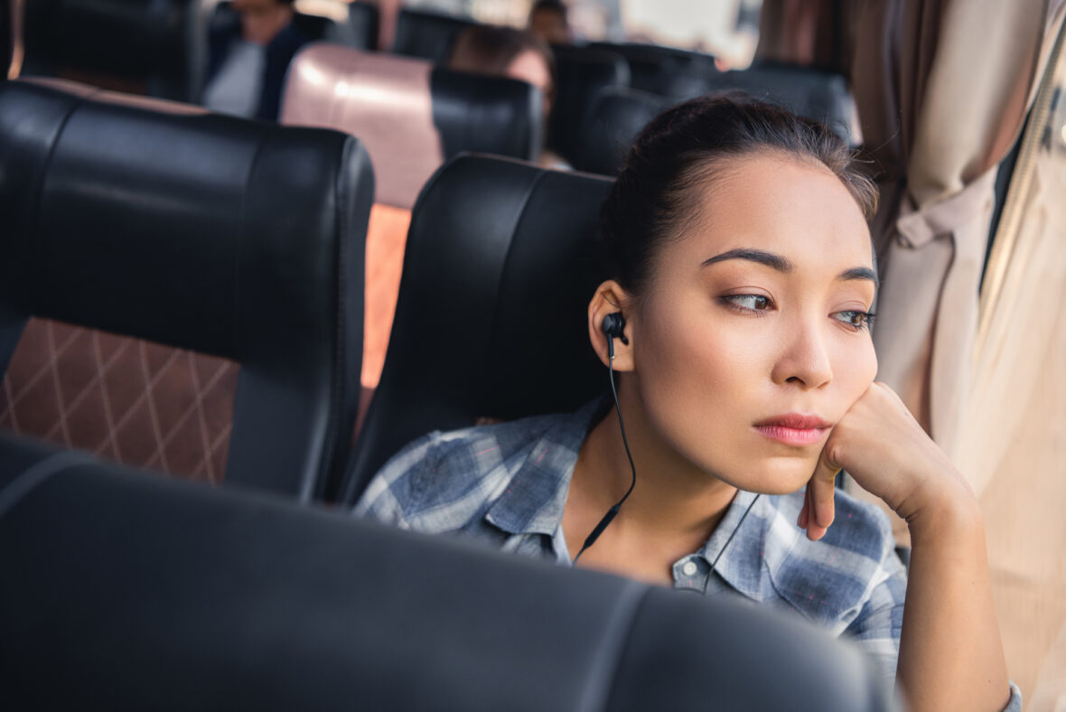 Thoughtful woman travelling on a bus while listening to music, reflecting during her journey