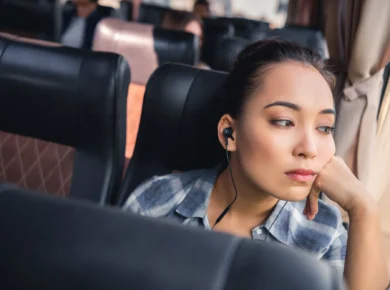 Thoughtful woman travelling on a bus while listening to music, reflecting during her journey
