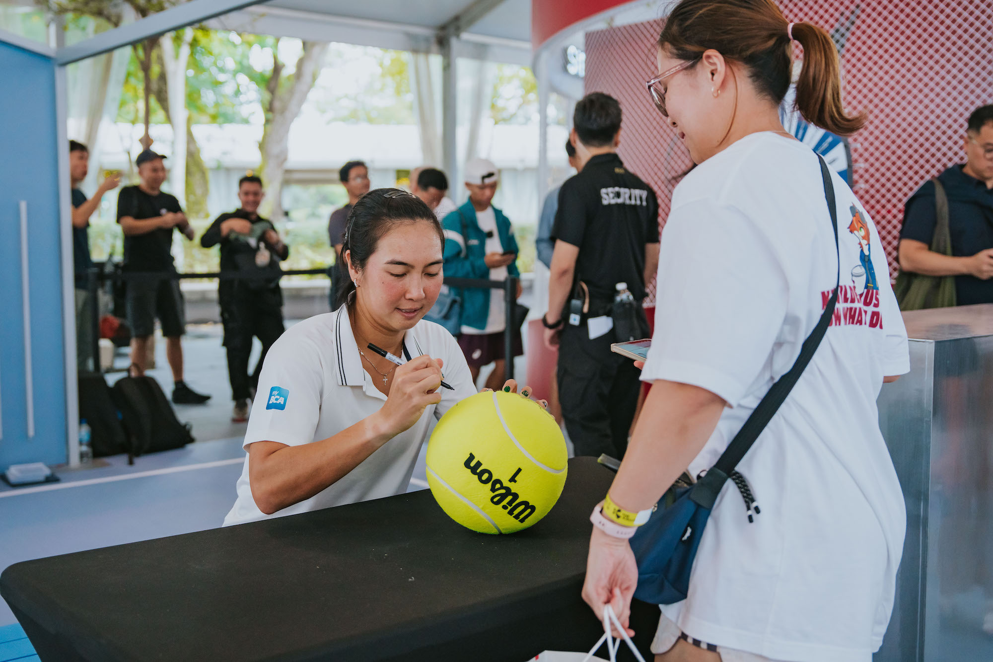 Aldila Sutjiadi signs a giant tennis ball for a fan during a meet-and-greet at the Singapore Tennis Open 2026.